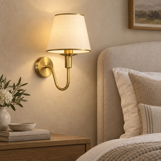 Curved arm shaded wall sconce beside a bed