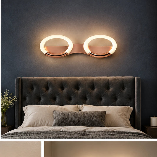 Rose-gold oval-ring wall light above a bed
