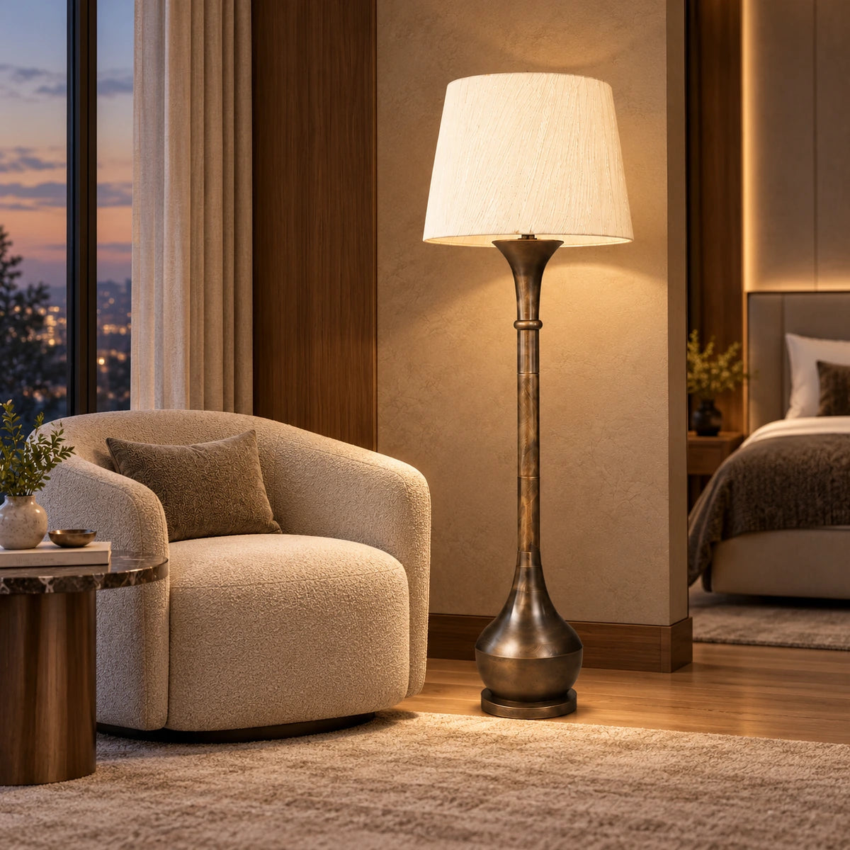 Antique-bronze column floor lamp beside a lounge chair in a bedroom seating corner