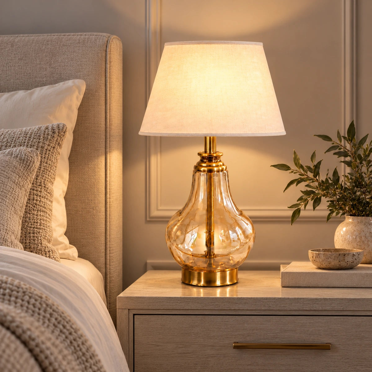 Amber glass table lamp illuminated beside a bed