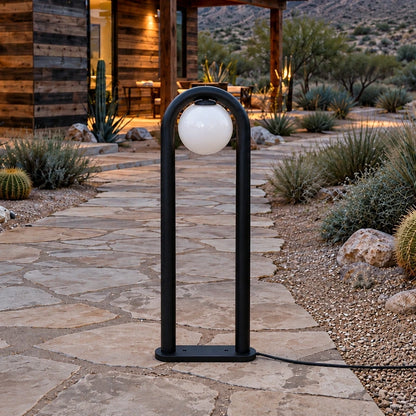 Arched globe matte-black LED bollard unlit beside a garden path