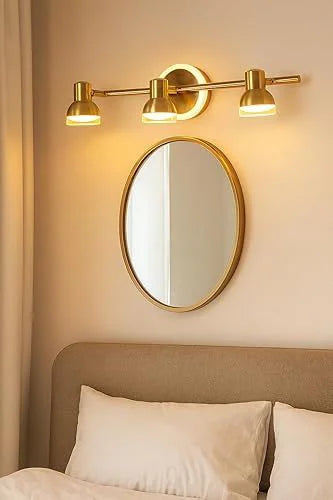 Golden triple-head vanity light above a bedroom mirror