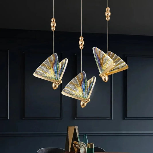Three butterfly mosaic pendants in a dark dining room