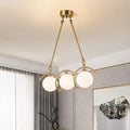 Three-globe brass linear chandelier in a living room