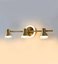 Golden triple-head vanity light illuminated on a wall