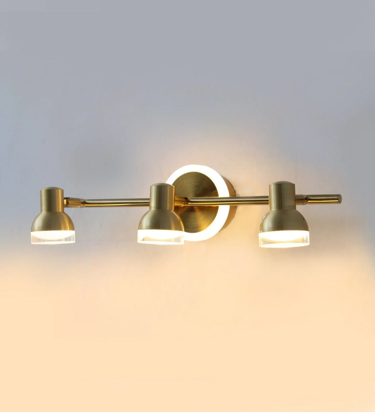 Golden triple-head vanity light illuminated on a wall