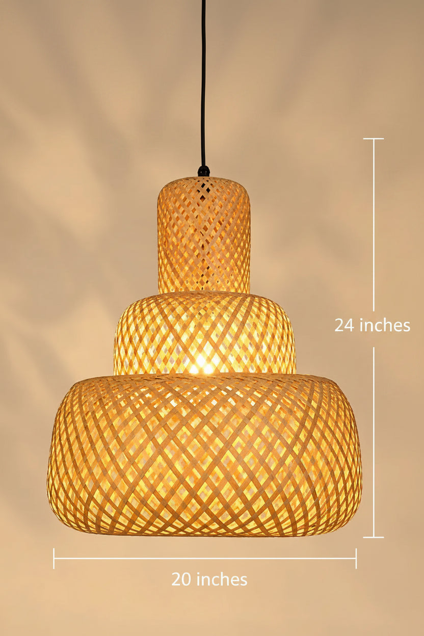 A three-tiered woven bamboo pendant light with a warm glowing bulb inside, set against a soft beige background with subtle leaf shadows.