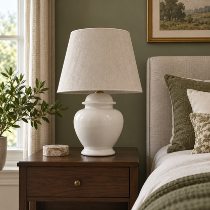 White ceramic urn table lamp on a walnut bedside table