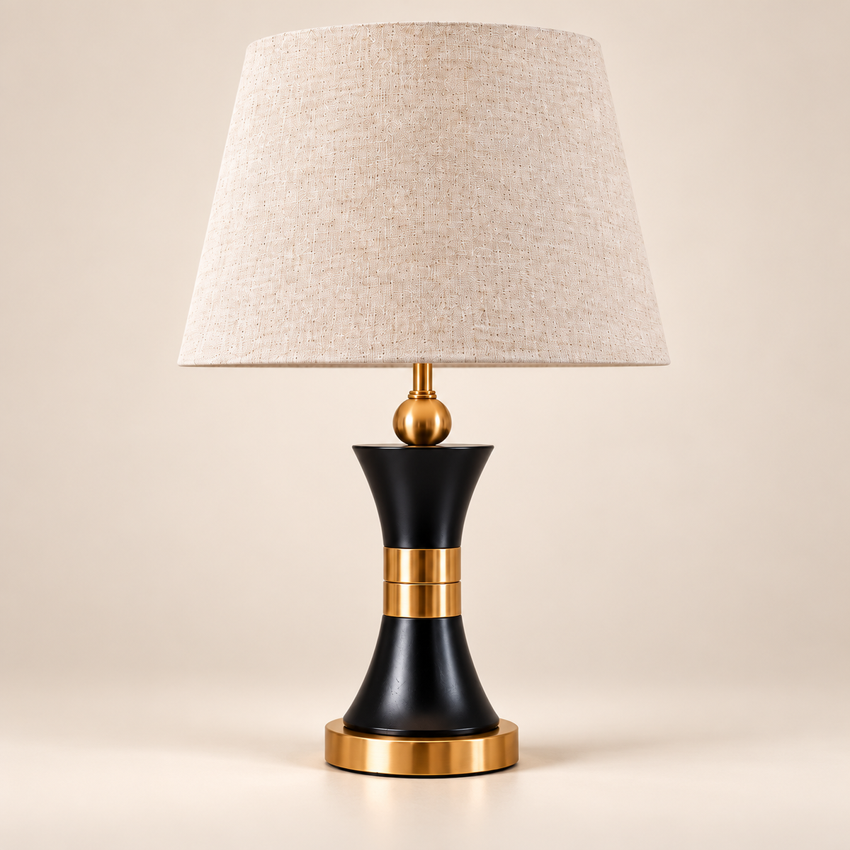 Black and gold hourglass table lamp with a light linen shade