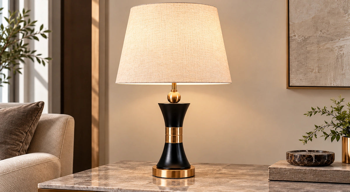 Black and gold hourglass table lamp on a marble console beside a sofa