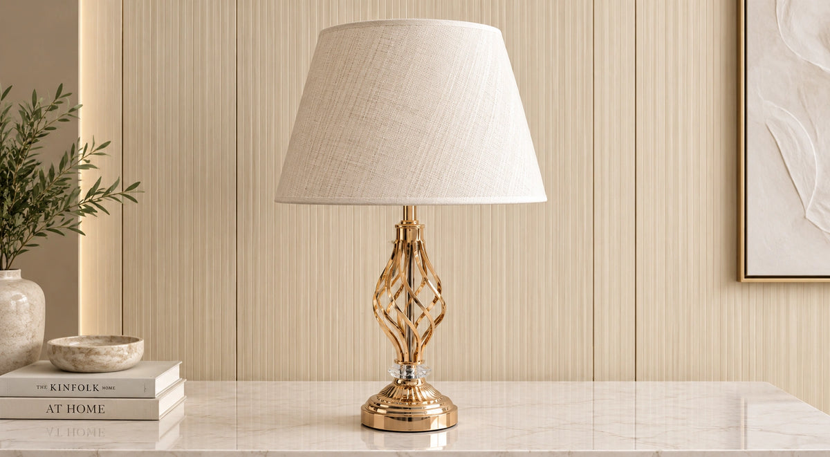 Gold twist table lamp on a pale console with cream fluted wall