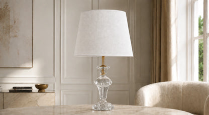 Crystal pedestal table lamp on a pale console beside a cream chair