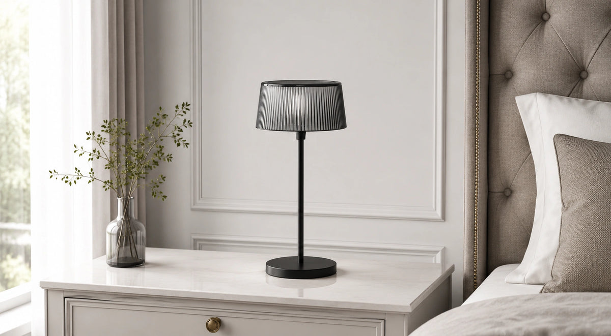 Noir Ribbed black table lamp switched off on a bedside table