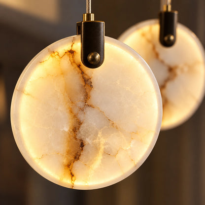 Close-up of illuminated marble disc and dark suspension fitting