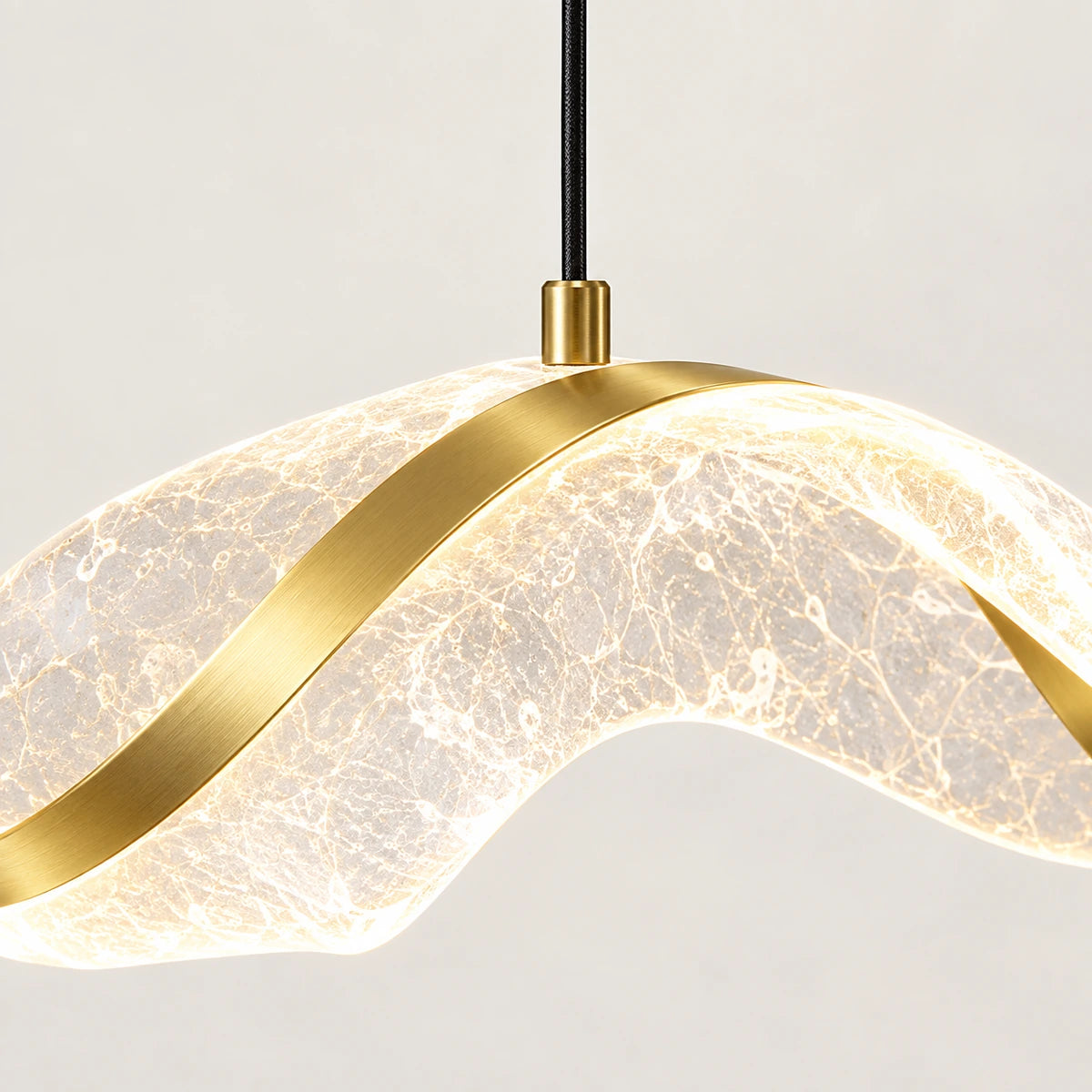 Close-up of translucent acrylic wave, gold-tone strip and cable attachment