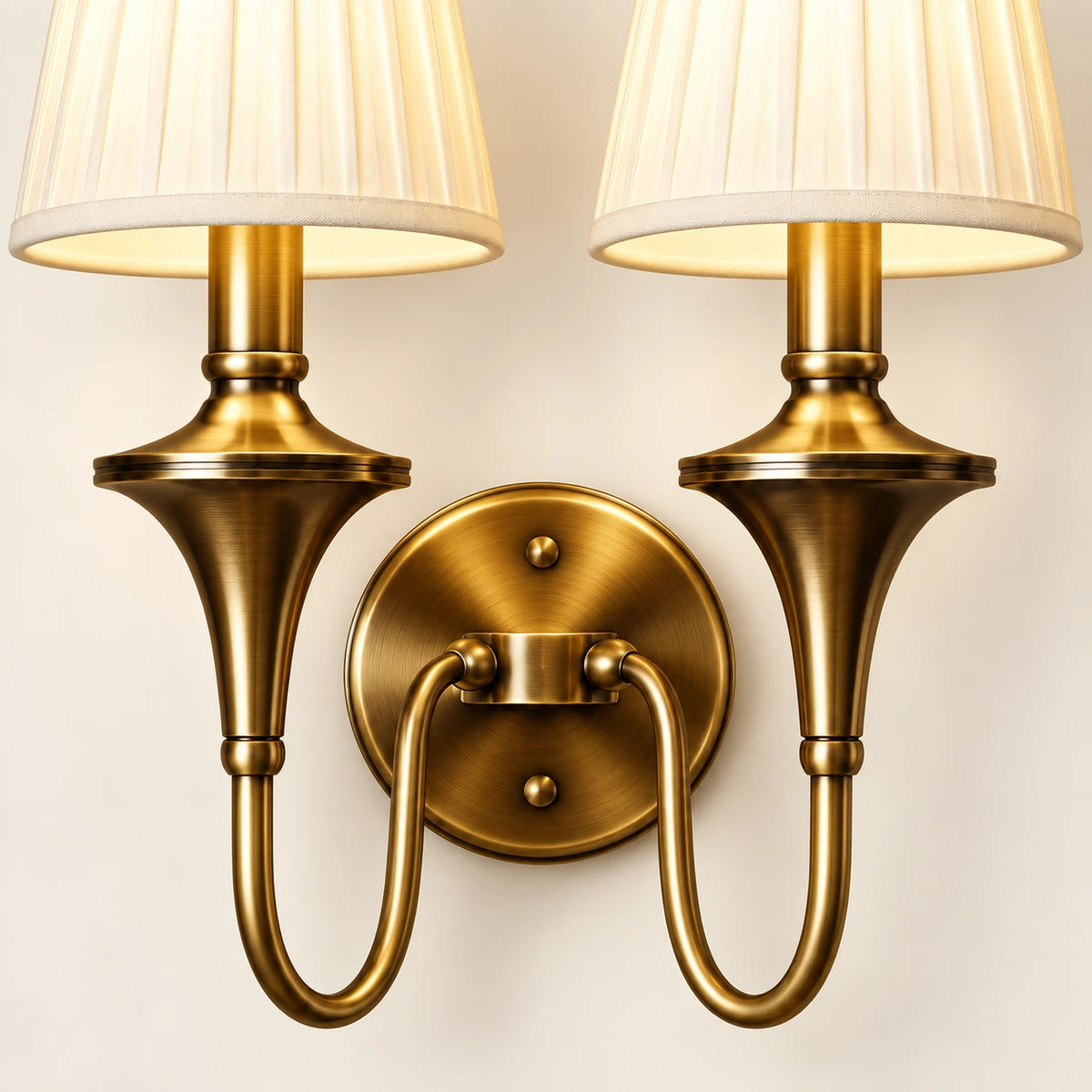 Close-up of both pleated shades, turned stems, twin curved arms and round wall plate