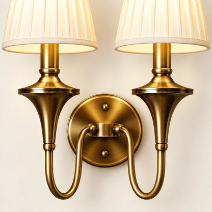 Close-up of both pleated shades, turned stems, twin curved arms and round wall plate