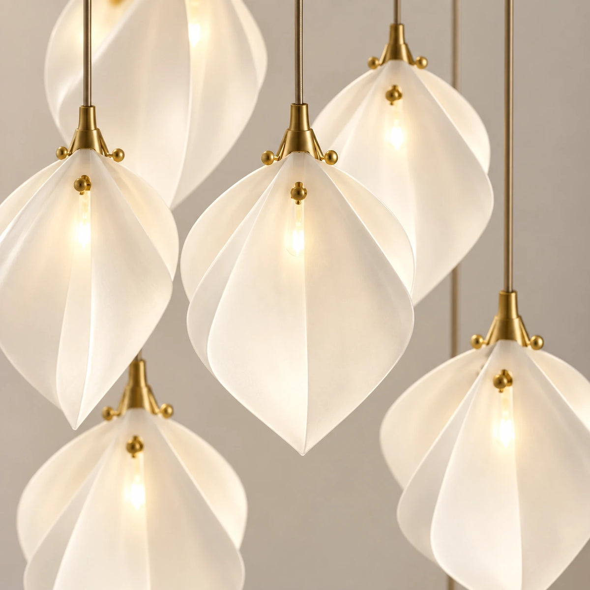 Close-up of the folded white petal shades, gold-toned caps and suspension cables