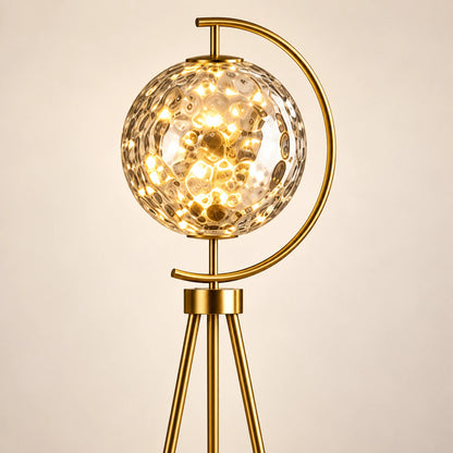 Close-up of patterned glass globe, gold arc and tripod connection
