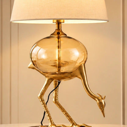 Close-up of the Aurelia crane lamp's amber glass globe and gold-tone sculpted bird detail