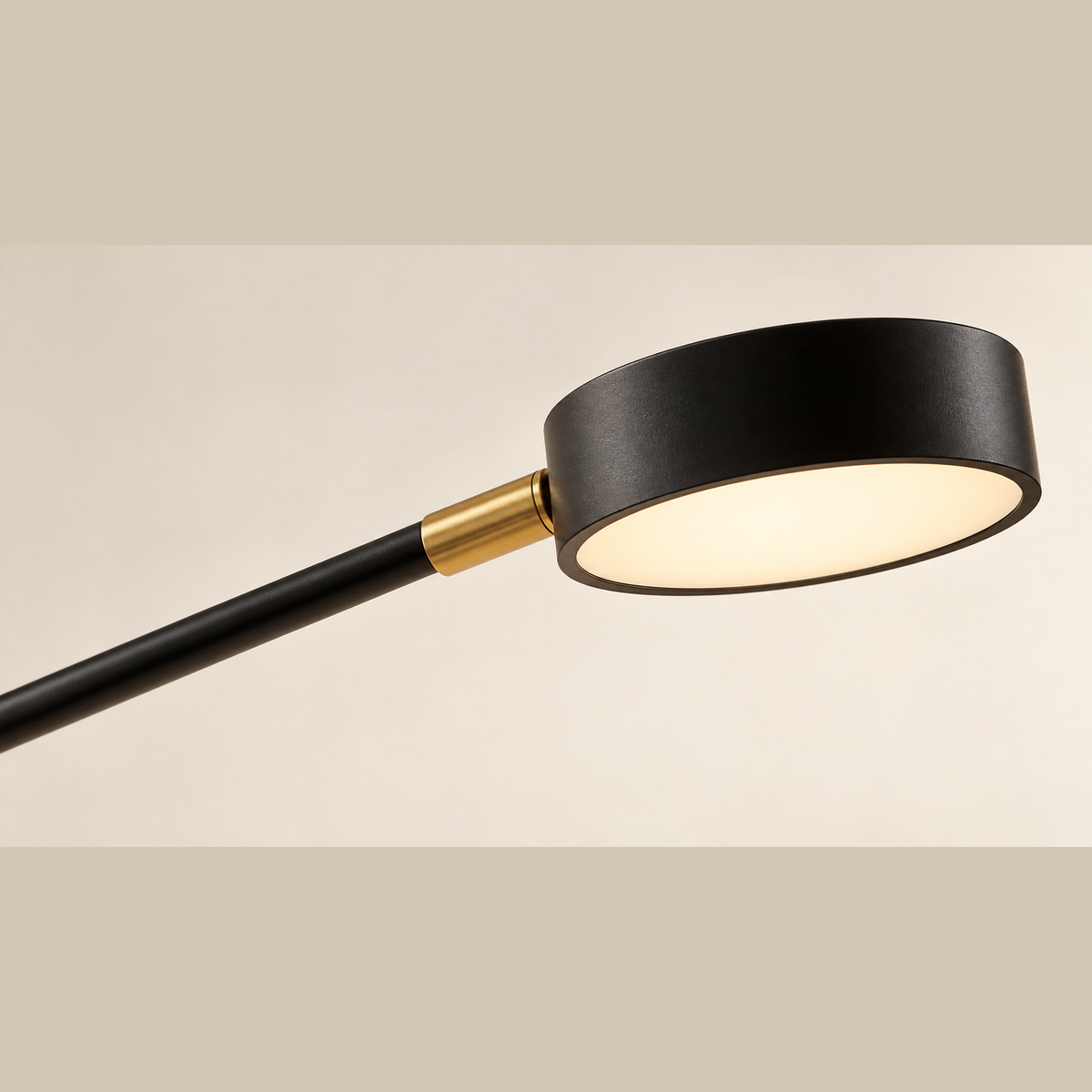 Close-up of the circular black lamp head, pale diffuser and gold connector