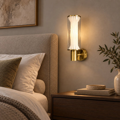 Fluted glass and gold wall light beside an upholstered bed