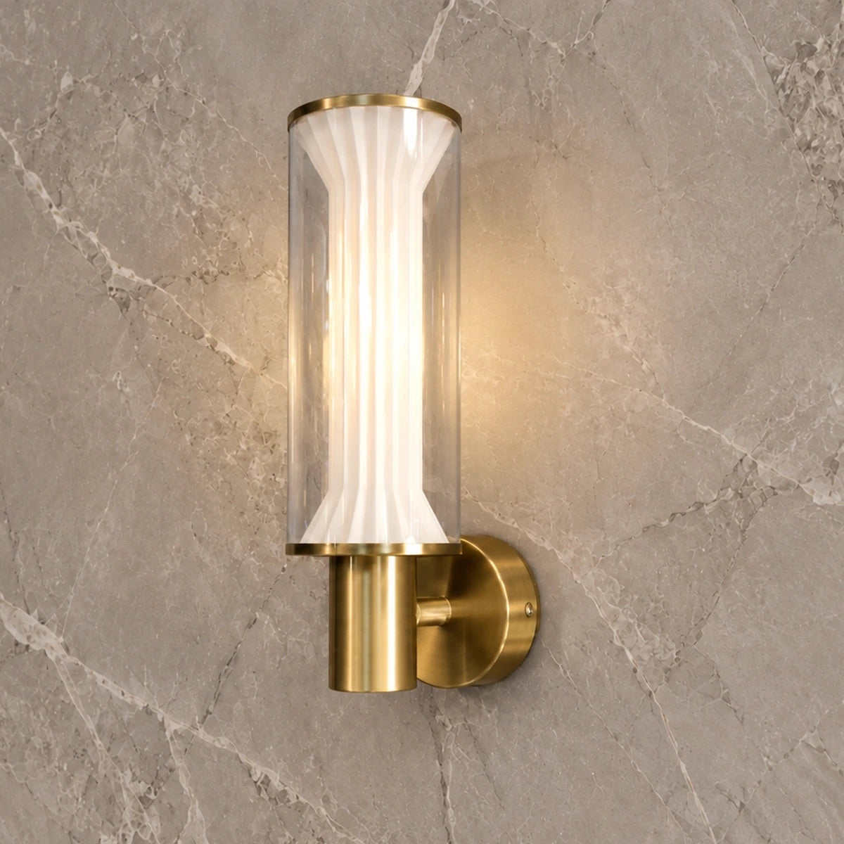Fluted glass and gold wall light illuminated