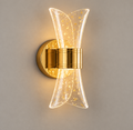 Gold wall light with clear curved hourglass shade