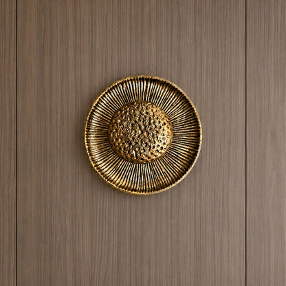 Gold sunburst wall light on a wood-panelled wall