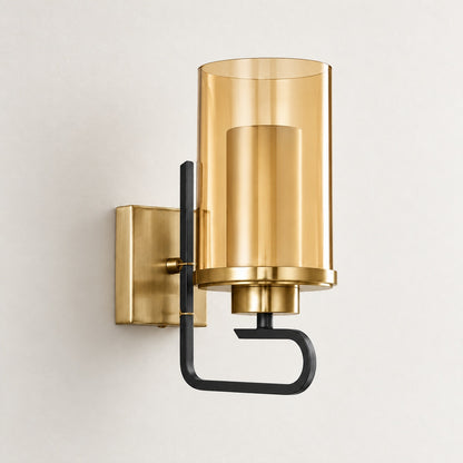 Aurelia amber-cylinder wall sconce with a gold-tone backplate and matte-black open-hook frame on a neutral wall