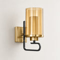 Aurelia amber-cylinder wall sconce with a gold-tone backplate and matte-black open-hook frame on a neutral wall