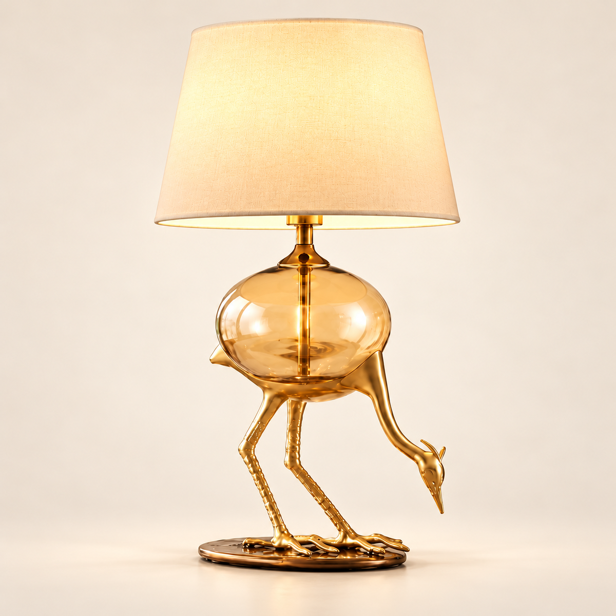 Aurelia gold-tone crane table lamp with amber glass body on a clean warm-white background