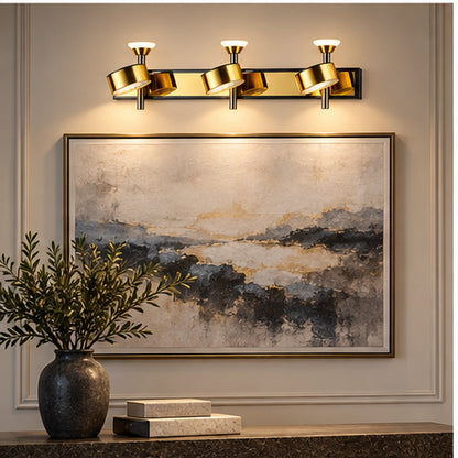 Gold three-head adjustable wall light above framed artwork