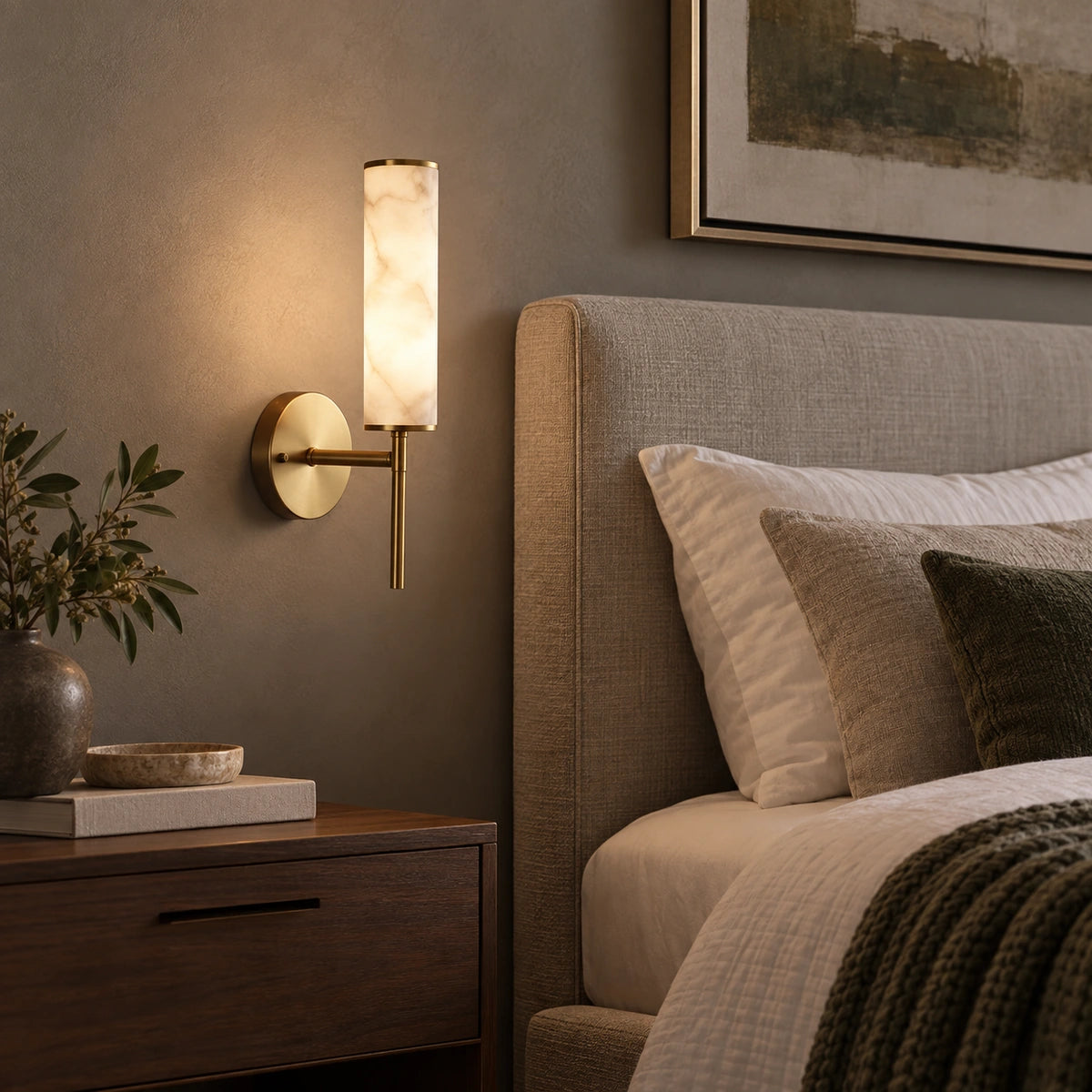 Alabaster-look cylinder wall sconce beside a bed