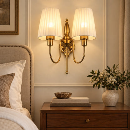 Twin pleated-shade wall sconce beside a bedroom headboard