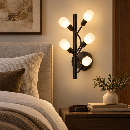 Five-globe black branch wall sconce beside a bed