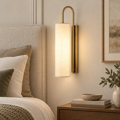 Tall cylinder shade wall sconce beside a bed