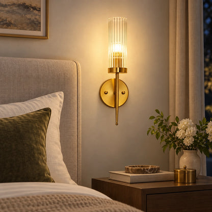 Ribbed glass cylinder wall sconce beside an upholstered bed