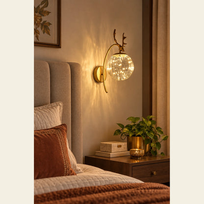 Antler bubble-globe wall sconce beside a bedroom headboard