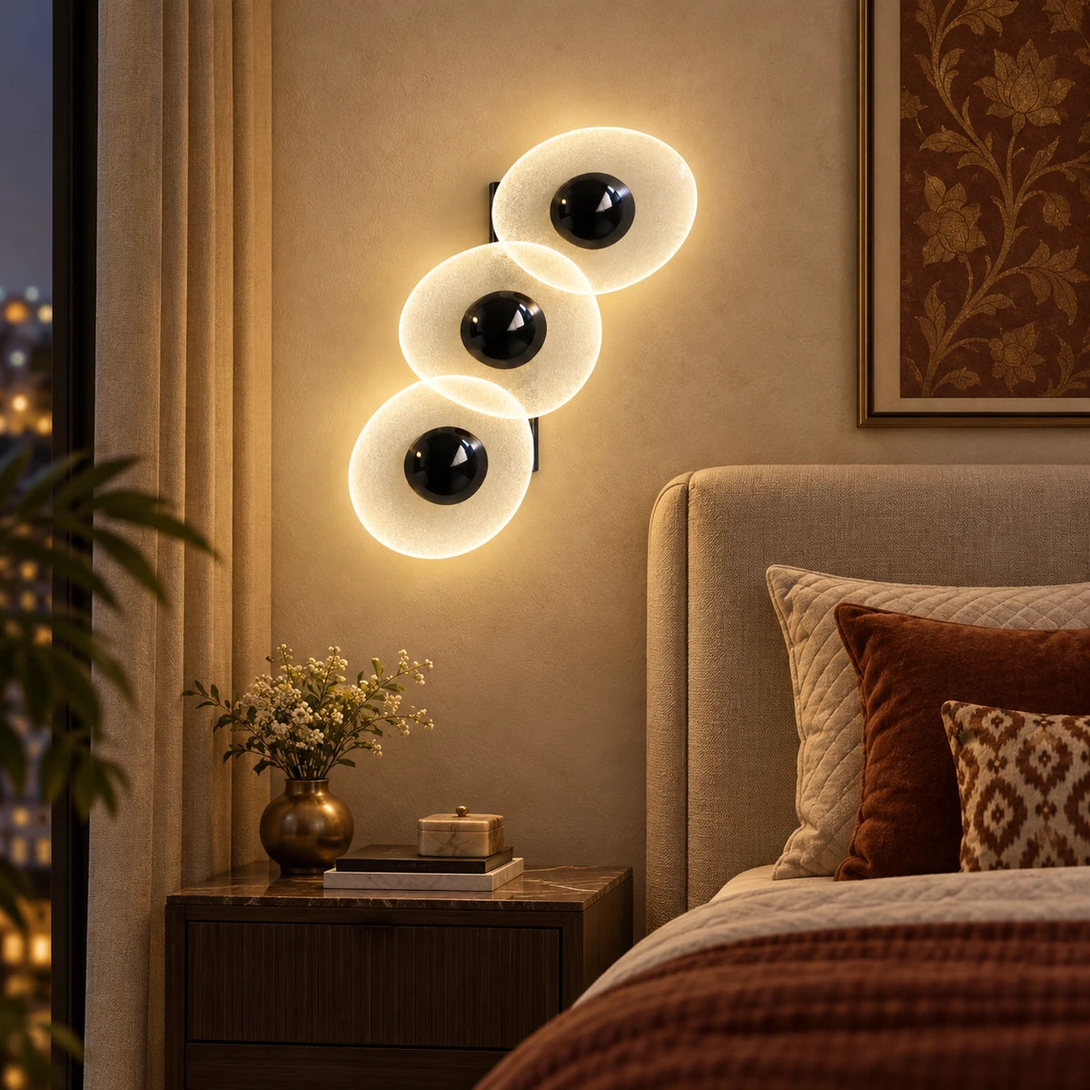 Triple oval illuminated wall art beside a bed