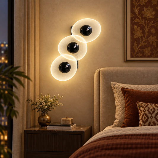 Triple oval illuminated wall art beside a bed