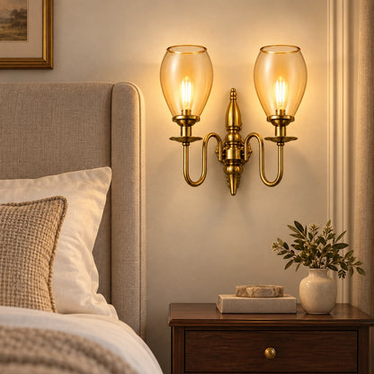 Twin amber tulip-shade wall sconce beside an upholstered bed