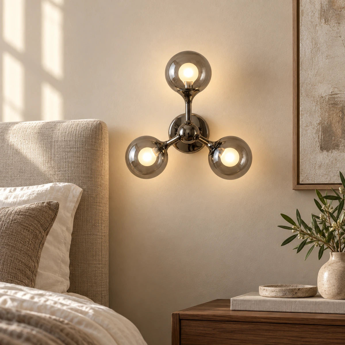 Three-globe smoke-glass wall sconce beside a bed