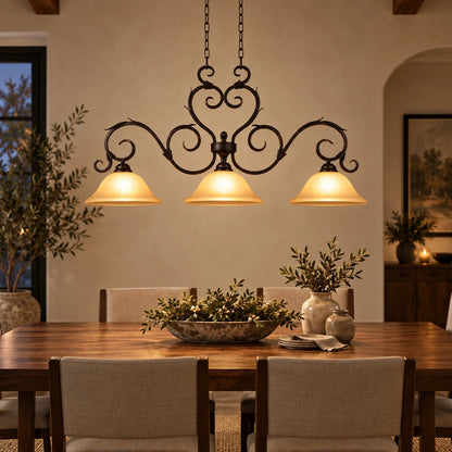 Antique-scroll three-shade linear pendant above a dining table