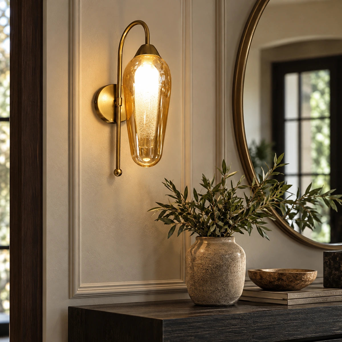 Amber capsule glass wall sconce above an entry console