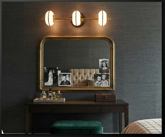 Supplier photograph of Marwa 5912/WL antique-brass and white three-light LED wall bar above a mirror; dimensions not stated