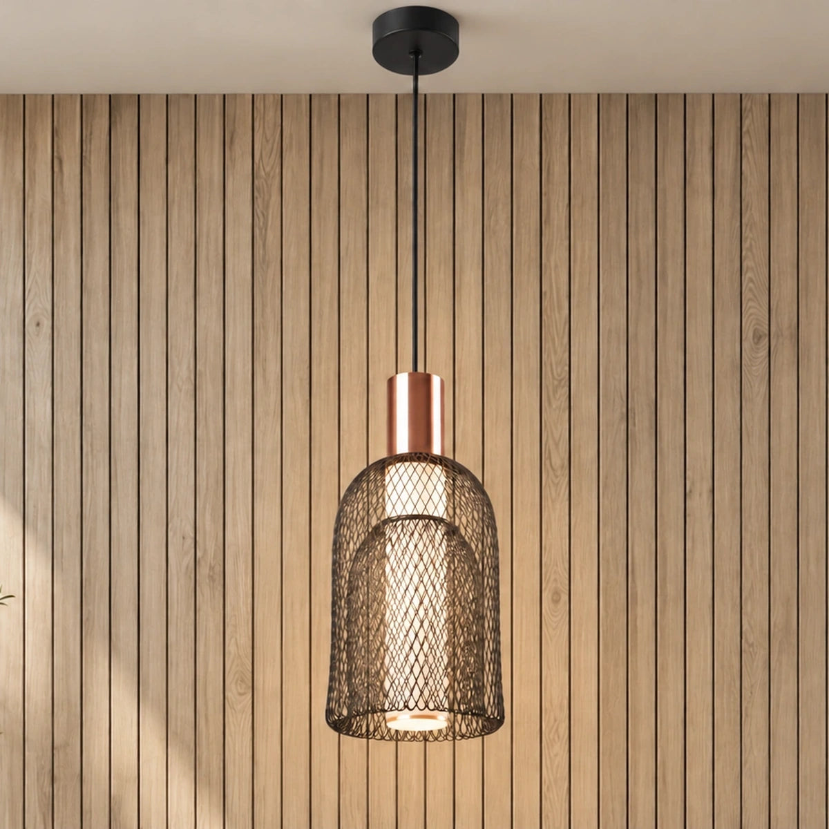 Nested black mesh and copper pendant light illuminated
