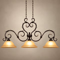 Antique-scroll three-shade linear pendant on a warm studio background