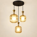Amber-glass three-light pendant cluster on a warm studio background