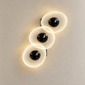 Triple oval illuminated wall art on a warm studio wall